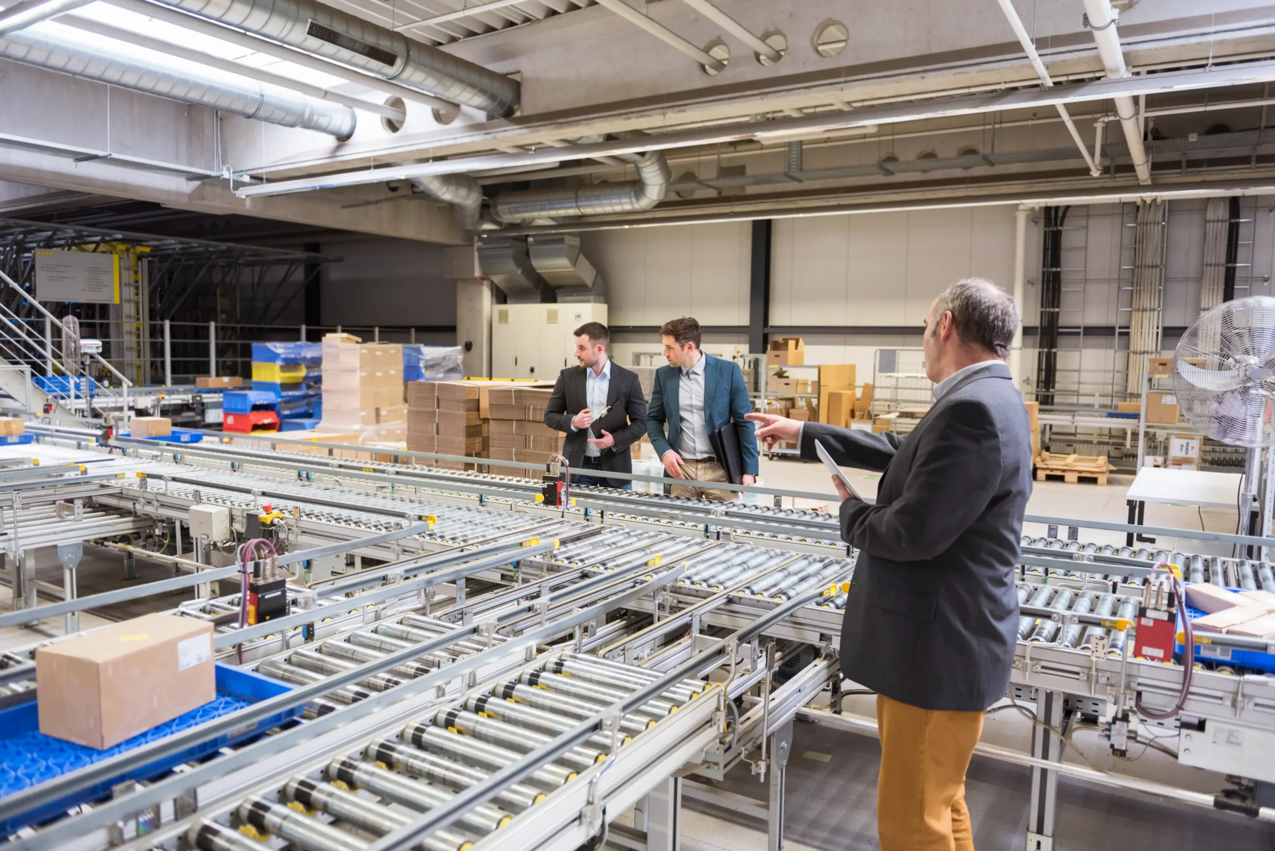 three-businessmen-at-conveyor-belt-in-factory-2026-01-05-00-39-35-utc